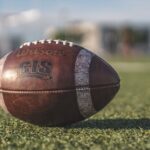 Close-up of a Wilson football on green grass in an outdoor sports setting, perfect for sports-themed visuals.